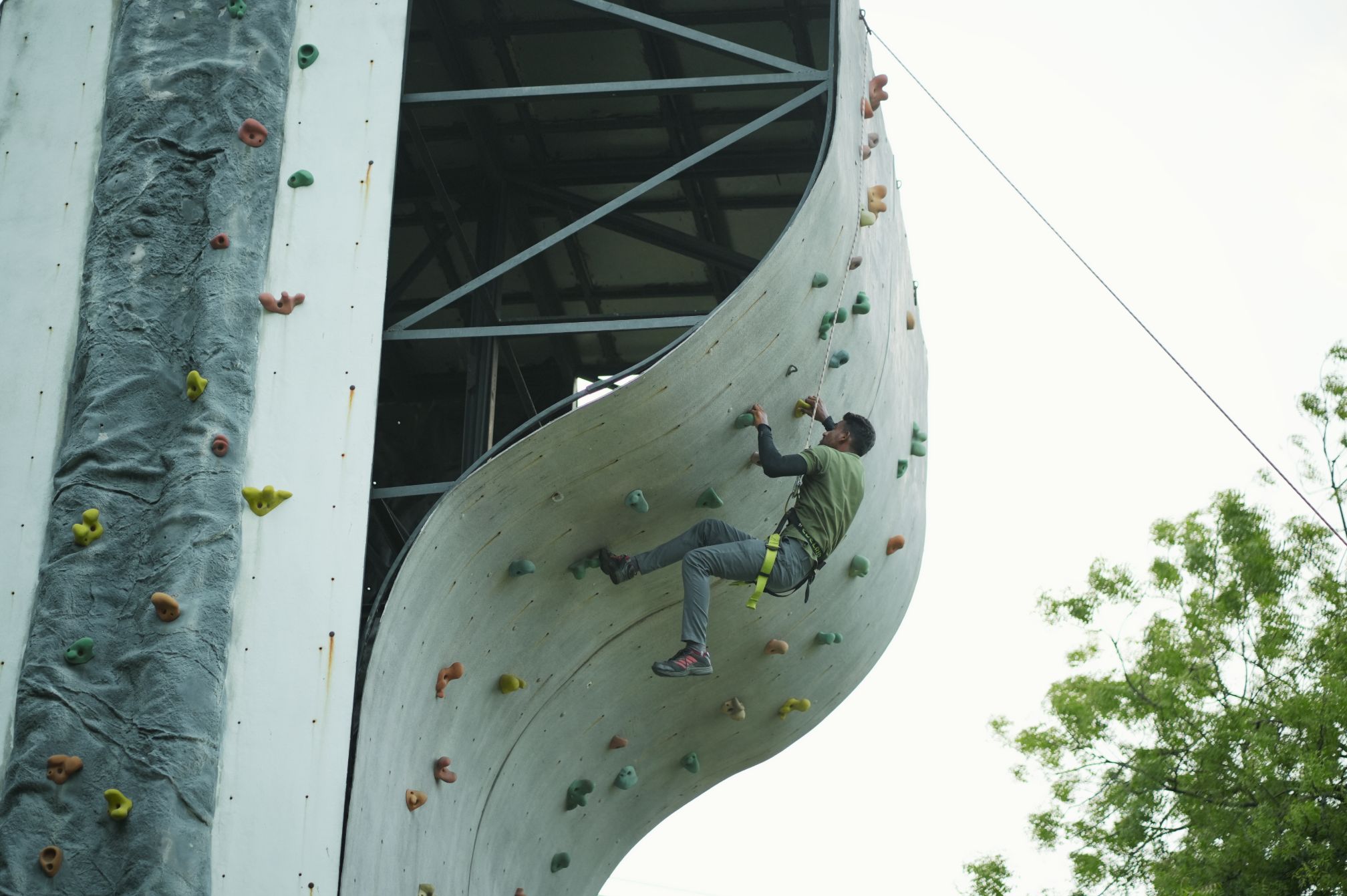 Man climbing outdoor wall at adventure resort in Ahmedabad during rope course
