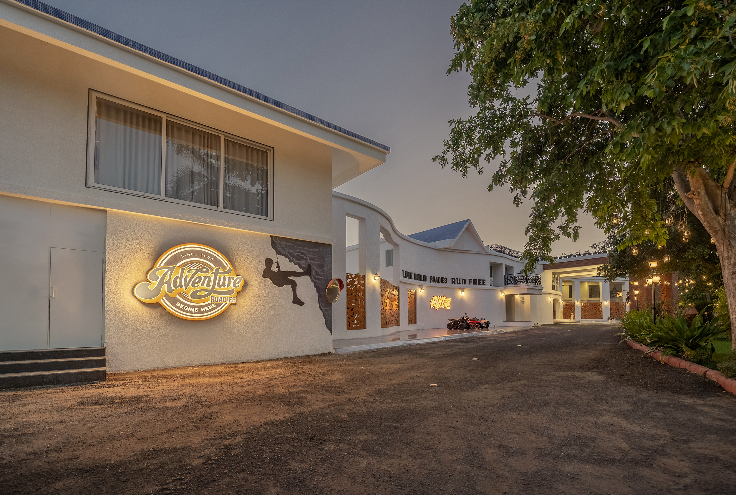 Front facade of Roadies Rostel ARC Resort at dusk with glowing lights, the best resort in Ahmedabad for staycations