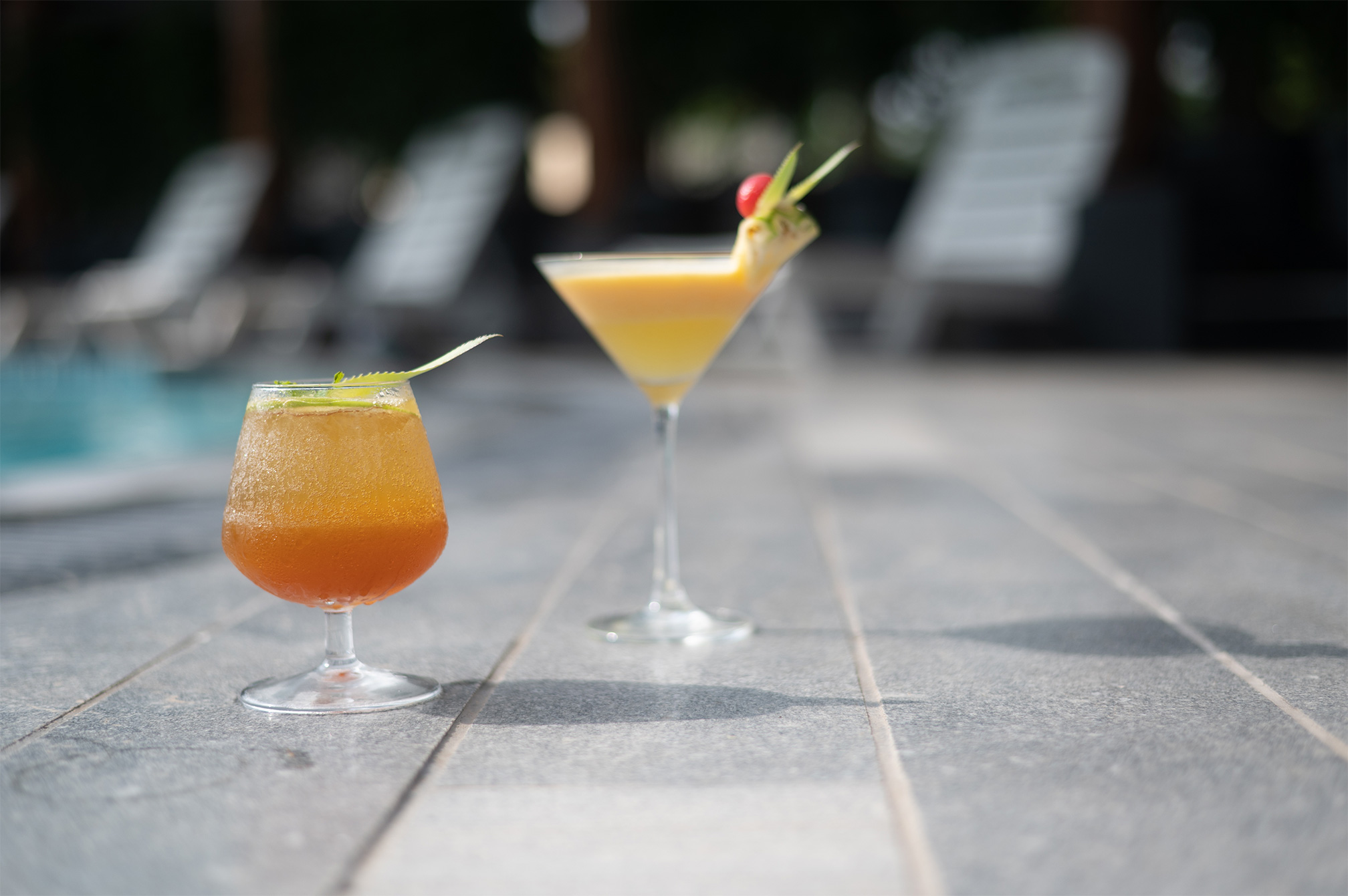 Colorful mocktails placed by the poolside at Roadies Rostel ARC Resort Ahmedabad, perfect for a refreshing moment during a one day picnic near Ahmedabad.