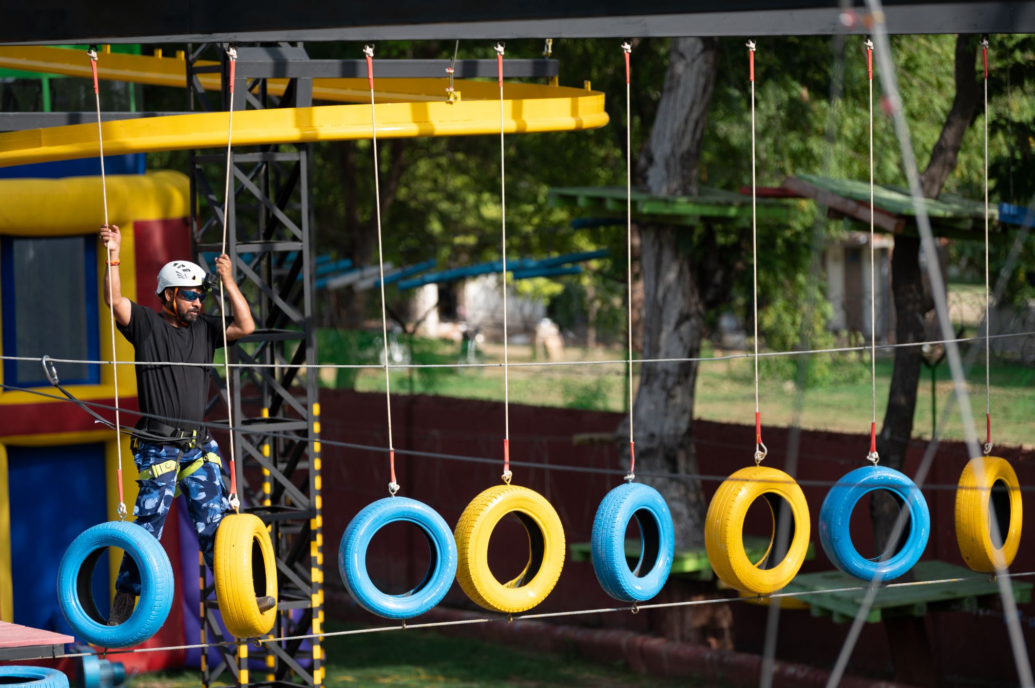 Guest crossing a hanging tire bridge on the adventure course at Roadies Rostel