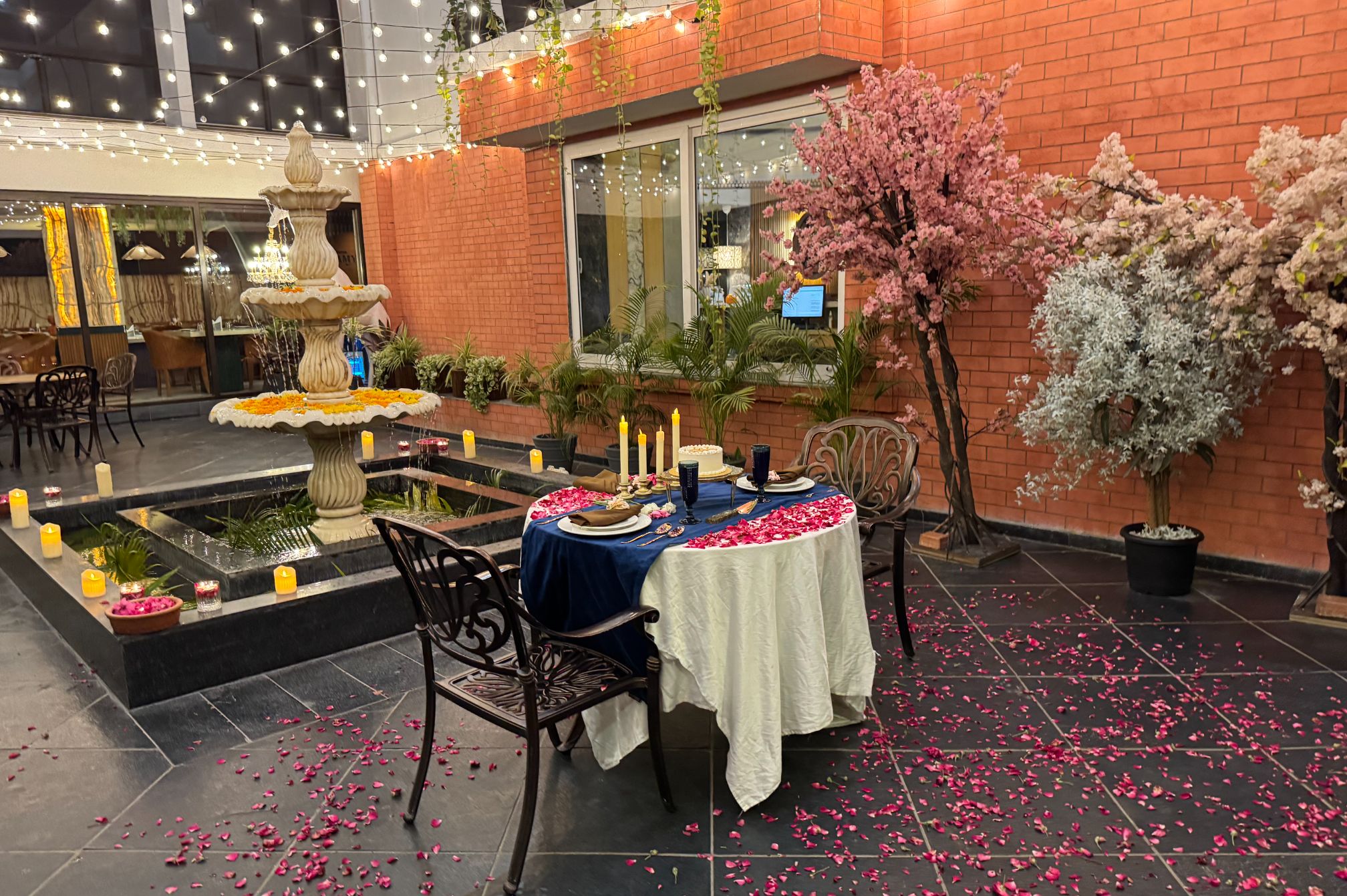 Elegant dining table near fountain with floral decor and warm lighting