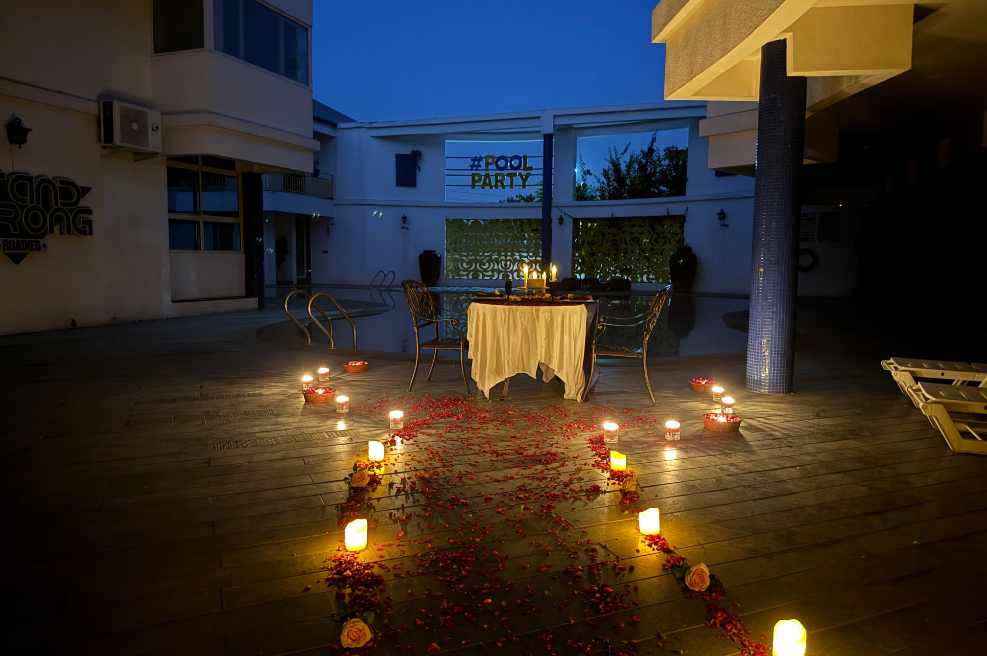 Romantic poolside dining at night with glowing candle path and ambient lighting