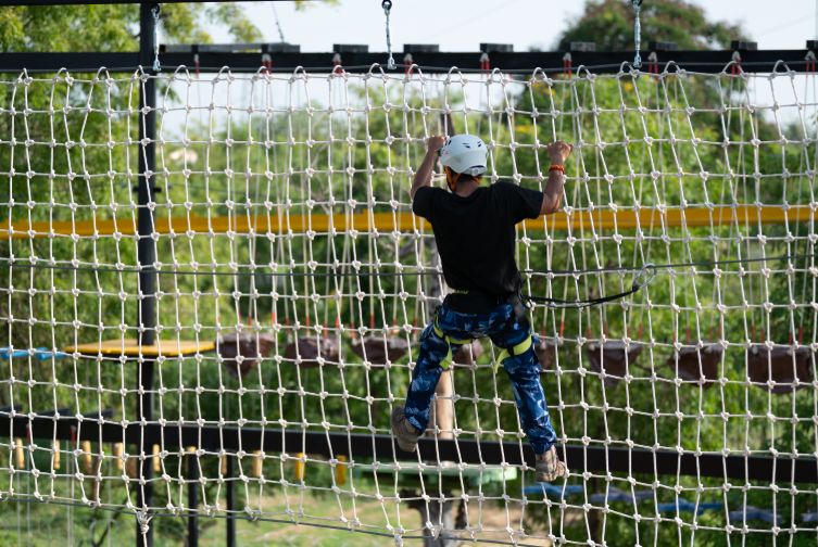 Guest climbing the rope net obstacle at Roadies Rostel ARC Resort adventure zone near Ahmedabad