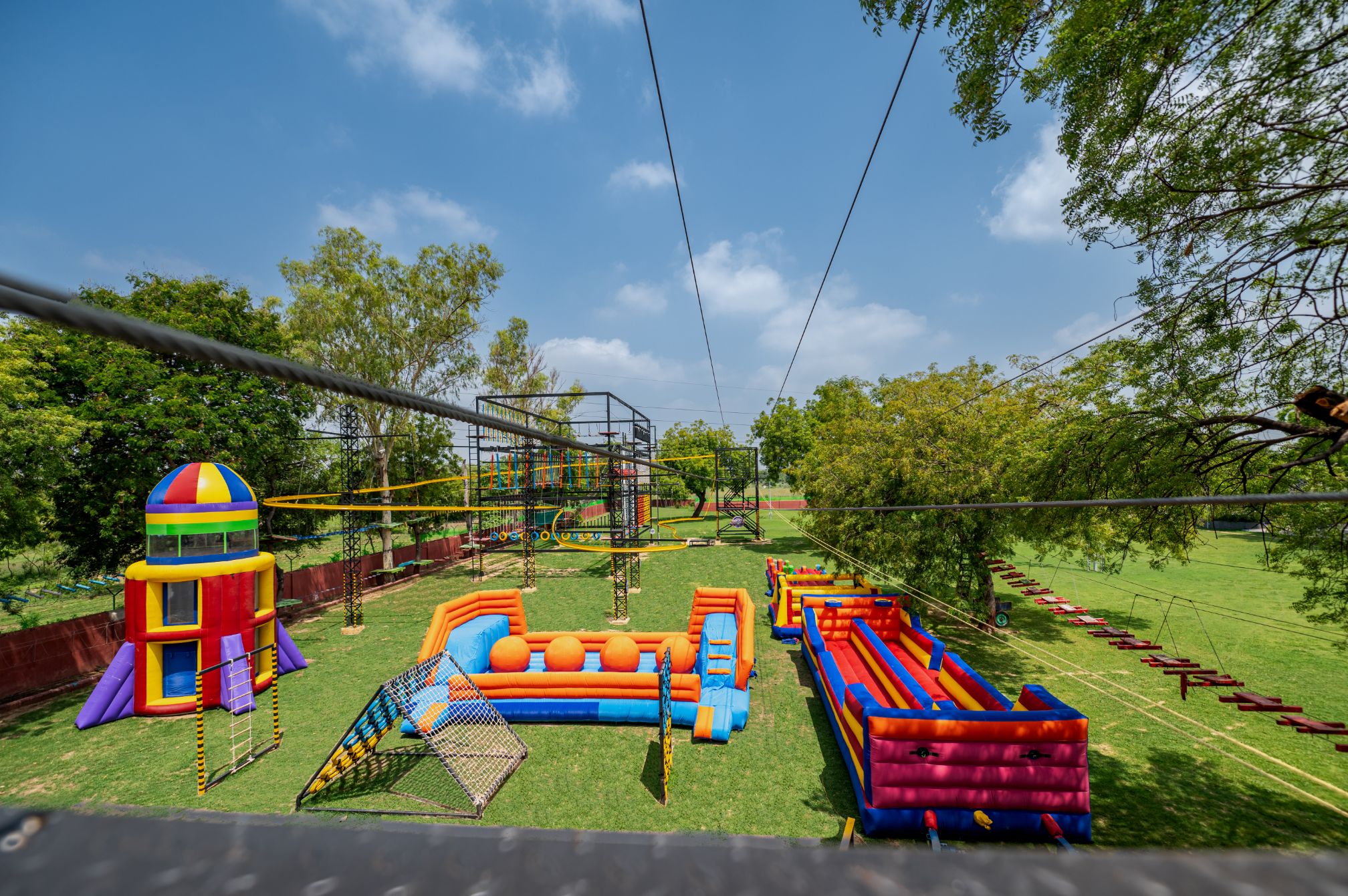 View of colorful inflatable park and rope activities from zipline track at Roadies Rostel ARC Resort near Ahmedabad