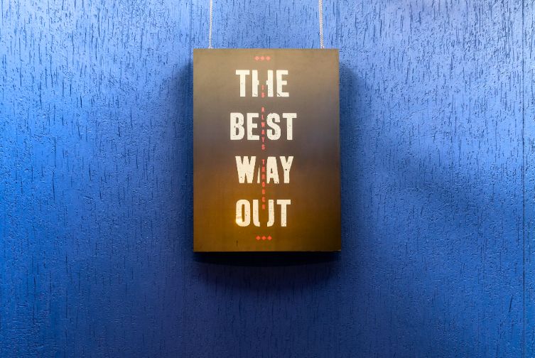 Motivational wall sign in den area reading 'The Best Way Out'