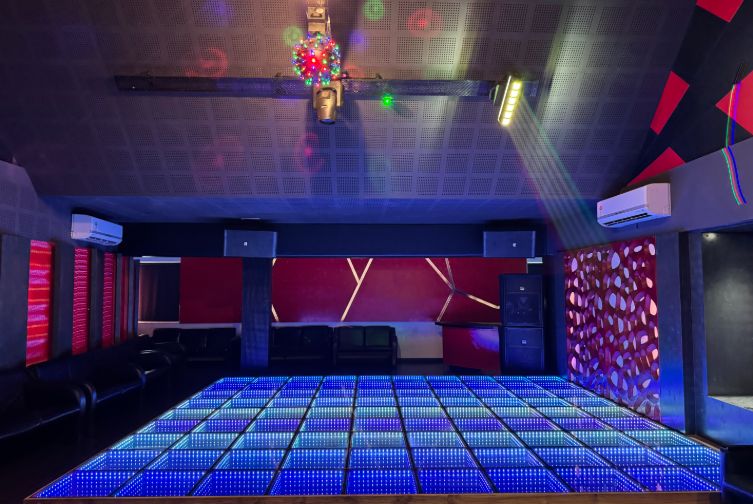 Wide view of glowing LED-lit discotheque dancefloor at Roadies Rostel ARC Resort