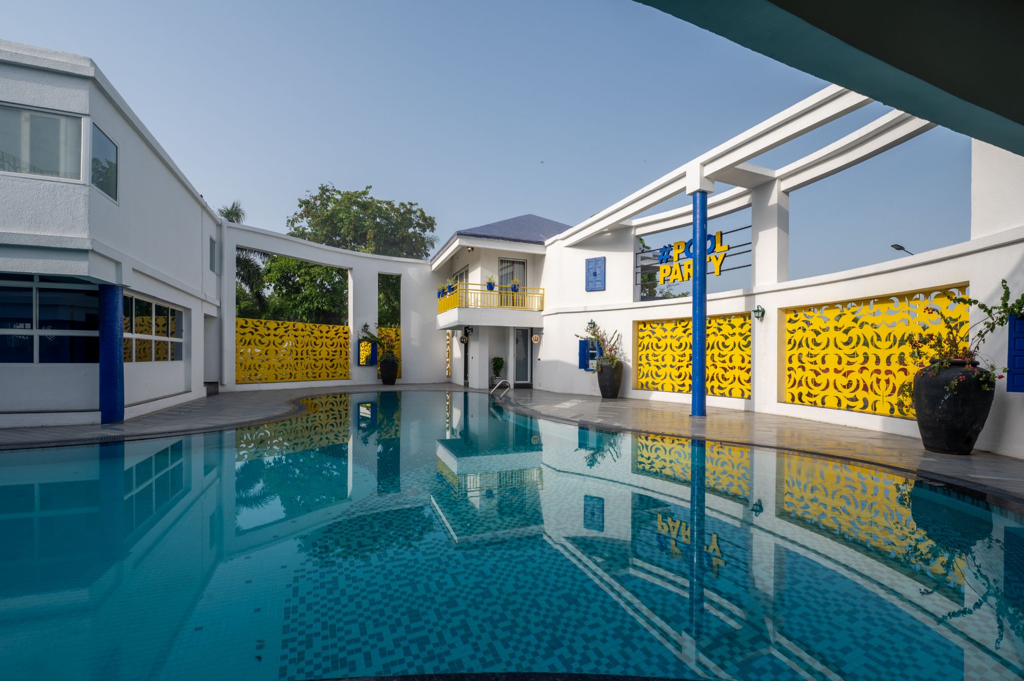 Serene poolside with blue and yellow accents at Roadies Rostel ARC Resort near Ahmedabad, ideal for a one day picnic near Ahmedabad.