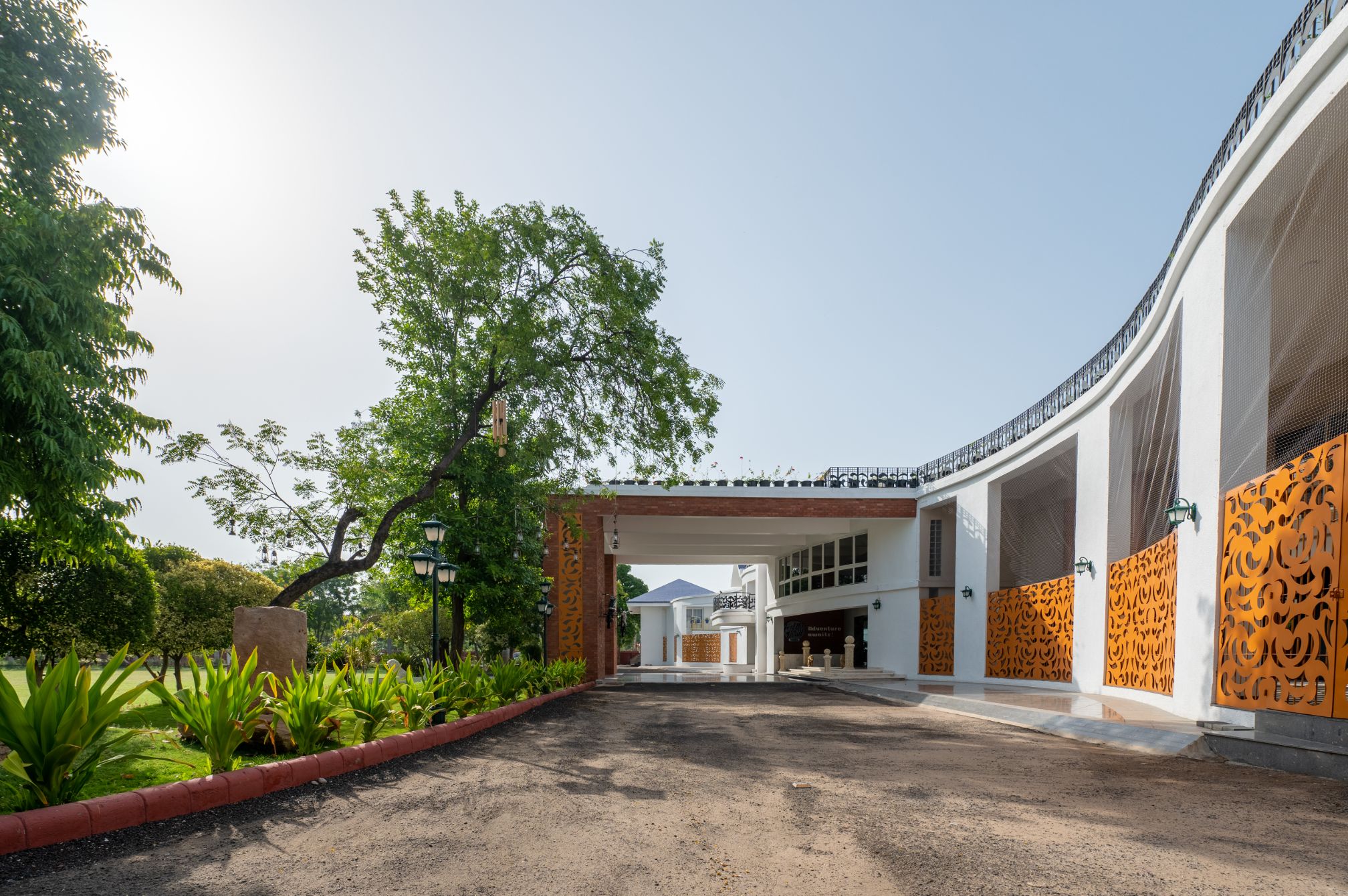 Curved entry driveway and landscaped front view of Roadies Rostel ARC Resort Ahmedabad