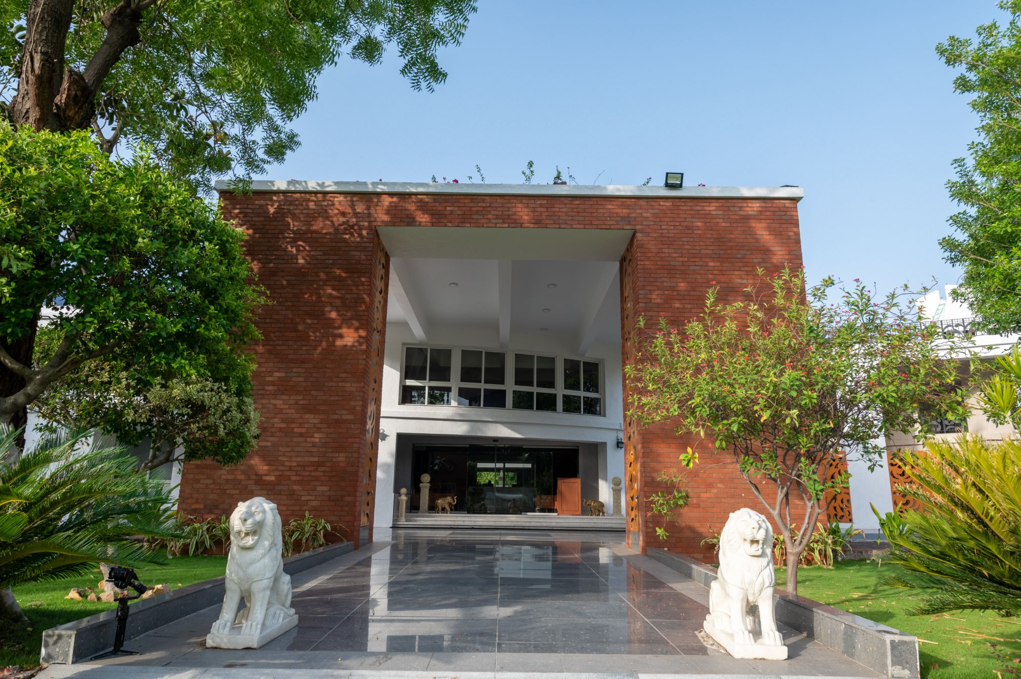 Grand front entrance of Roadies Rostel ARC Resort with lion statues and landscaped greenery, ideal for luxury weekend stays.