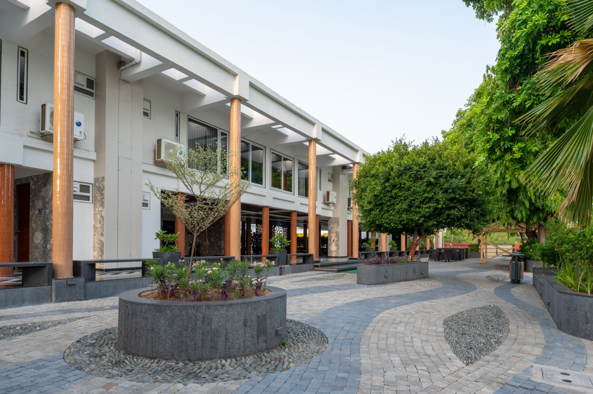 Beautiful curved stone walkway and outdoor seating at the entrance of Roadies Rostel Resort, offering a scenic welcome.