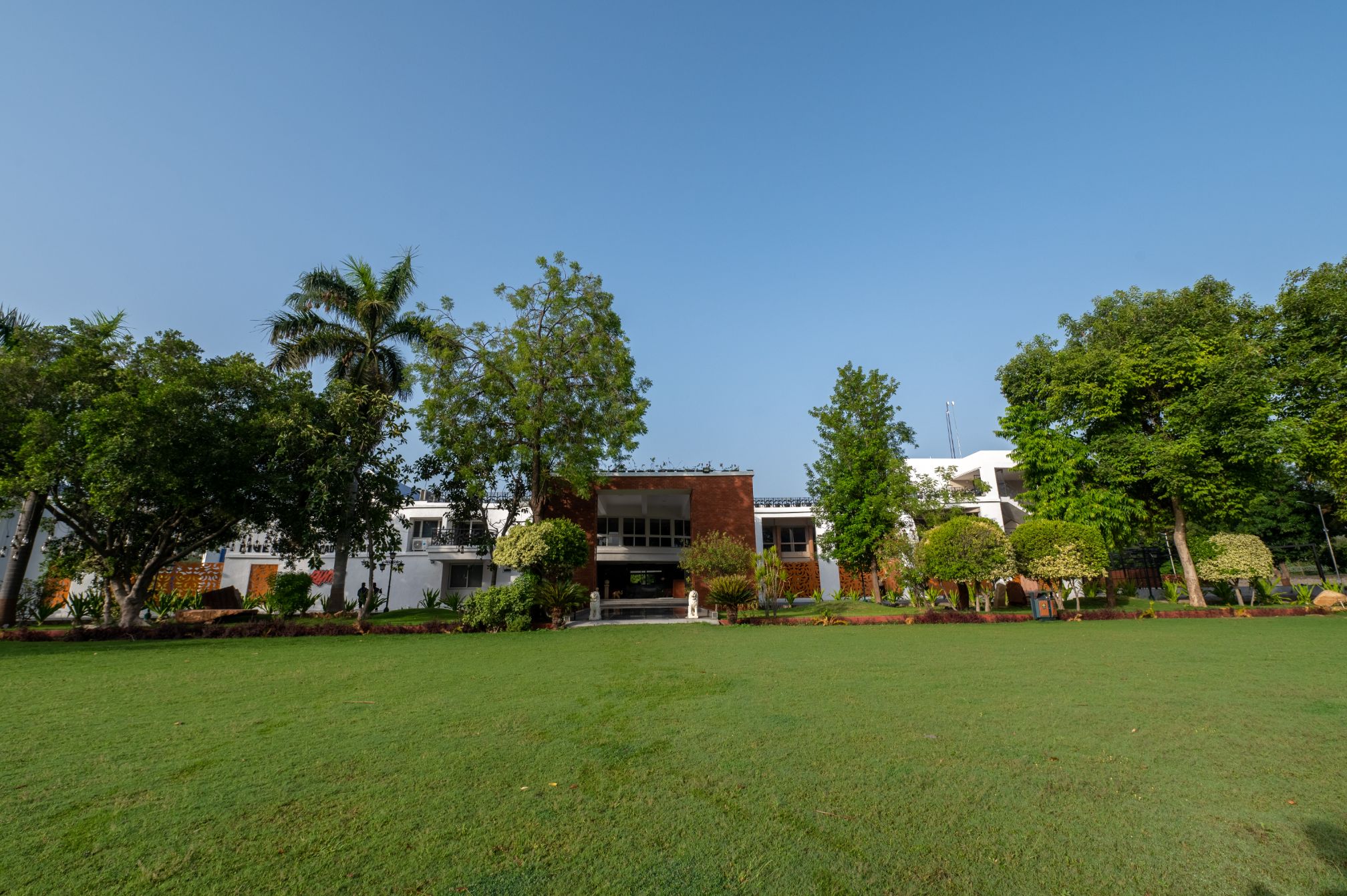 Lush green lawn with resort facade at Roadies Rostel ARC Resort near Ahmedabad