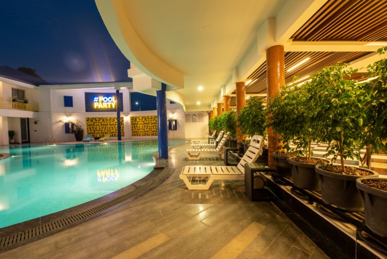 Poolside seating area at Roadies Rostel ARC Resort in the evening with lounge chairs and ambient lighting