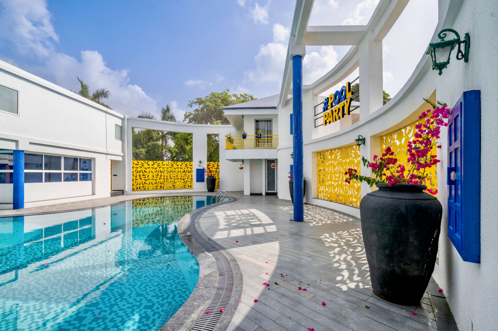 Bright daytime view of the poolside area at Roadies Rostel ARC Resort with colorful decor and seating