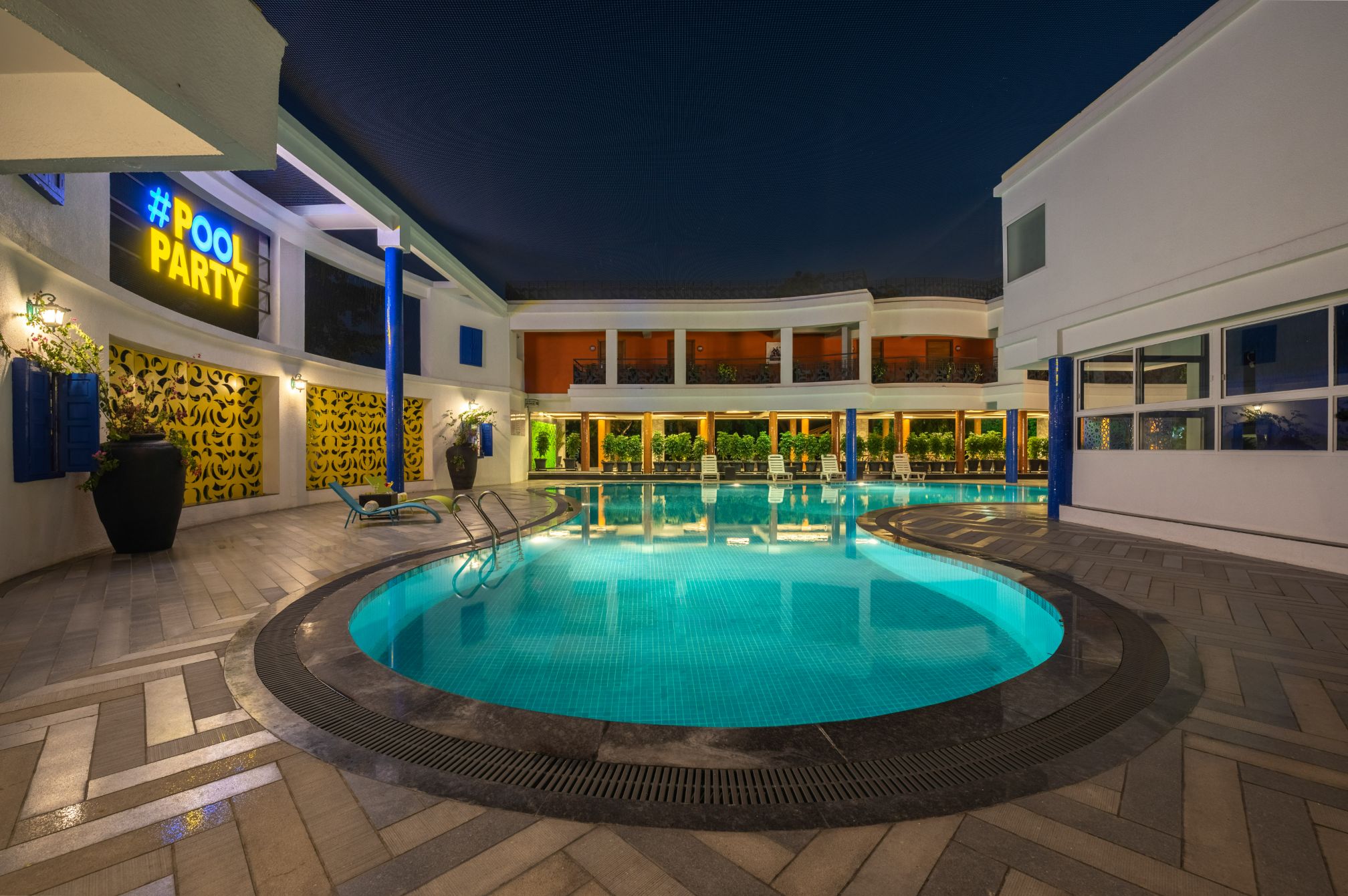 Illuminated pool party area at Roadies Rostel ARC Resort with stylish lighting and seating near Ahmedabad