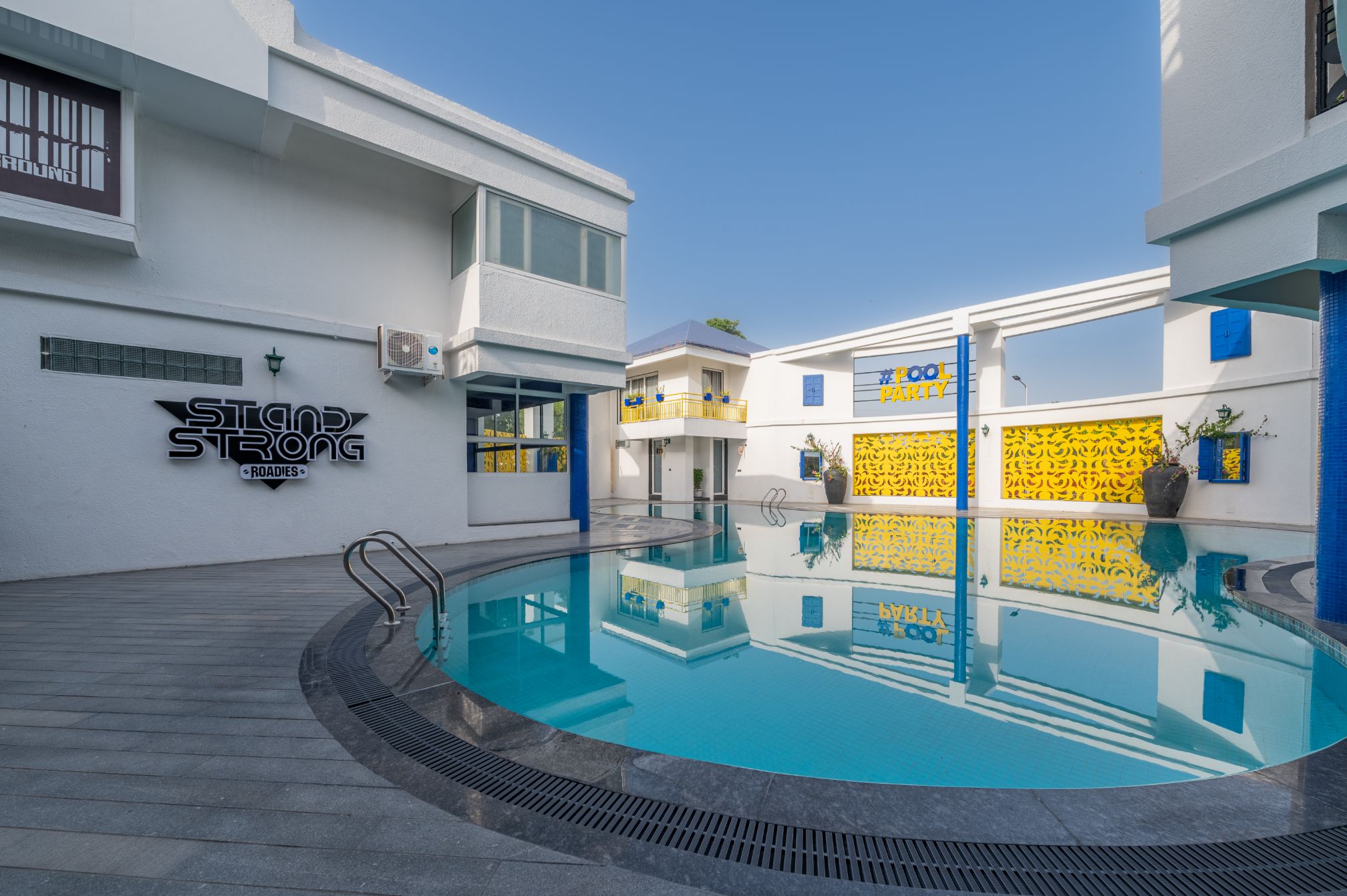 Poolside view near Stand Strong sign at Roadies Rostel ARC Resort with clean surroundings and vibrant walls
