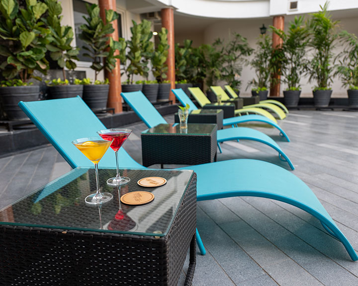 Comfortable poolside setup with sunbeds and cocktails at Roadies Rostel ARC Resort offering modern resort amenities in Ahmedabad