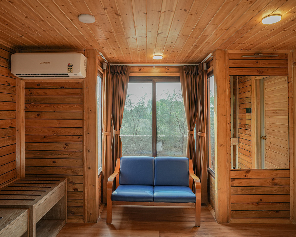 Deluxe Room design at Roadies Rostel ARC showcasing warm wall paneling and artwork for a stylish stay experience in Ahmedabad