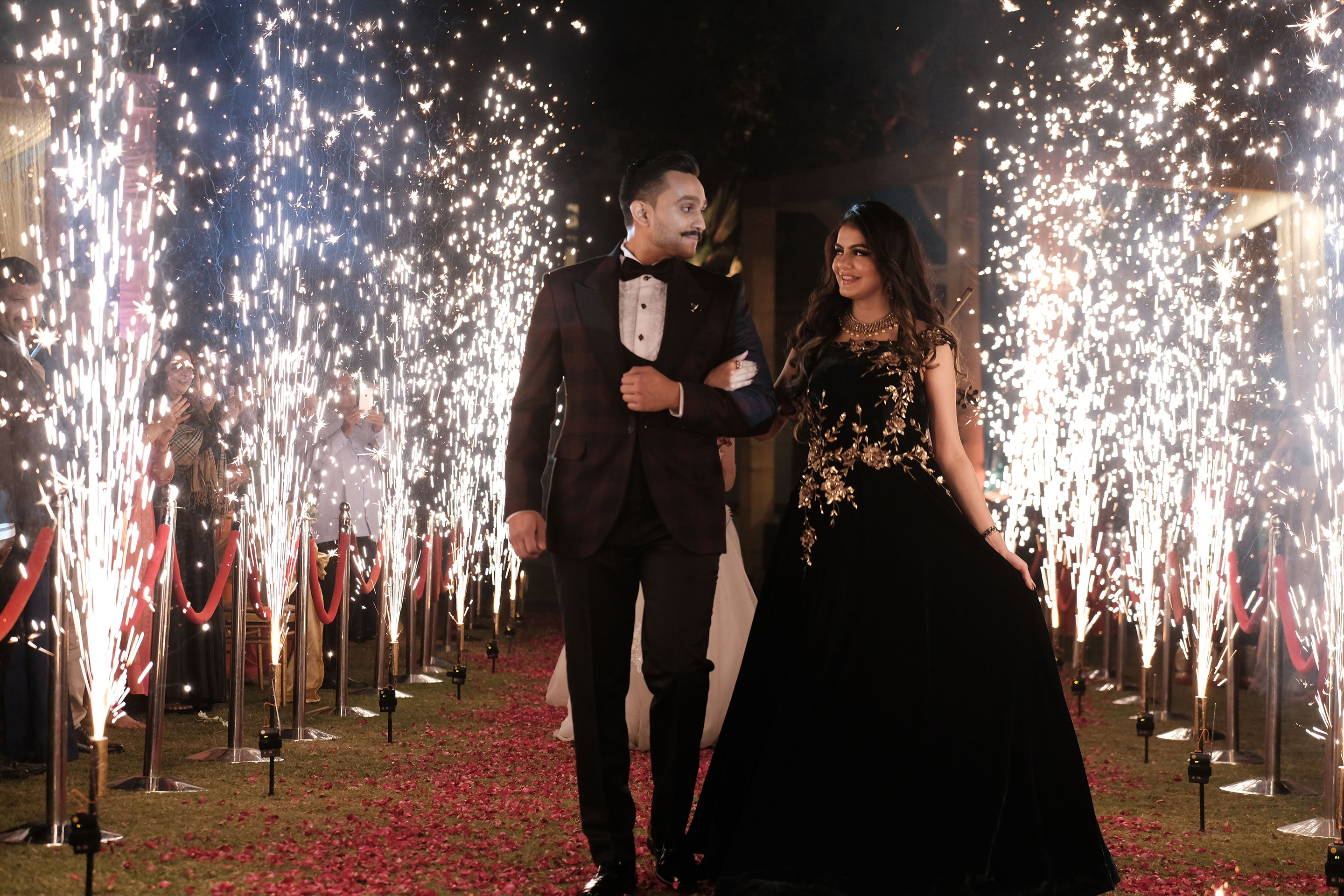 Bride and groom walking through a grand floral entrance at Roadies Rostel ARC Resort, the perfect wedding venue near Ahmedabad.